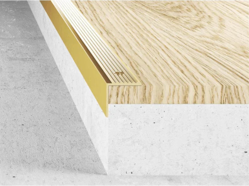 Close-up of a wooden floor panel with a white baseboard on a gray surface.