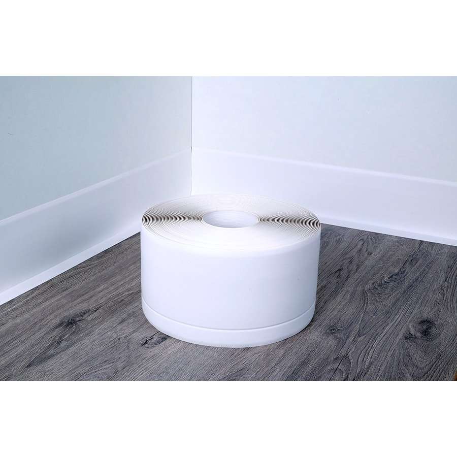 White roll of tape on a wooden floor with white walls.