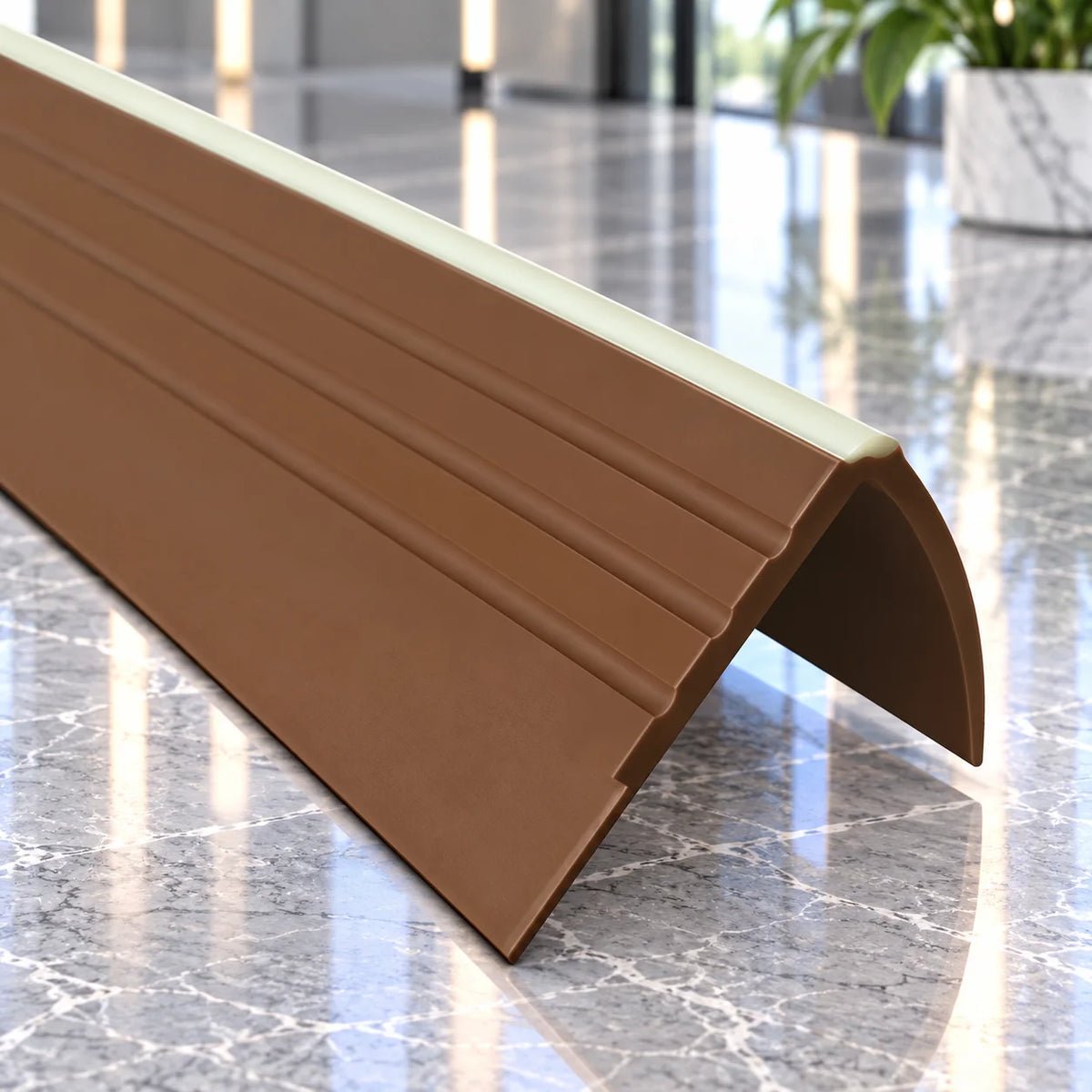 A curved brown PVC floor slope trim piece with grooved channels, shown on a polished gray marble floor with a blurred modern interior background.