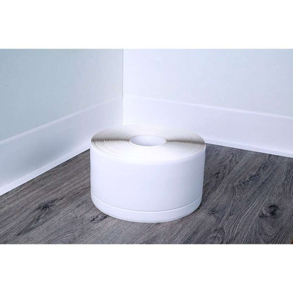 White roll of tape on a wooden floor with white walls.